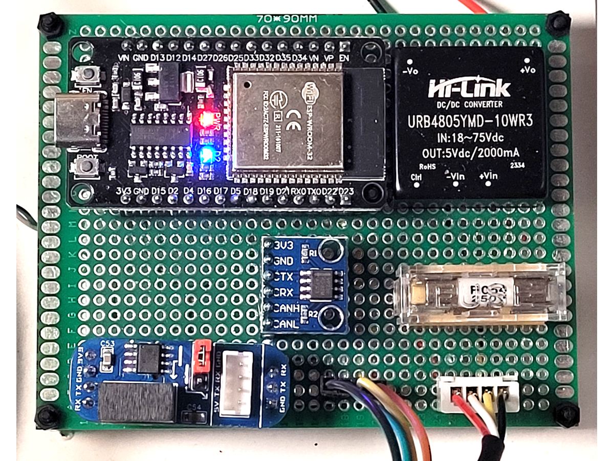 Photo of a green perfboard with an ESP32 development board, a black Hi-Link DC-DC converter module, a small blue CAN transceiver board and an RS485 adapter, all hand wired, with the ESP32 power LEDs lit