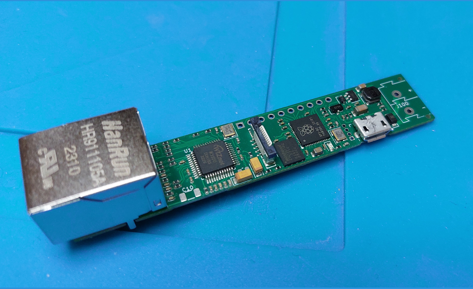 Top view of a long narrow green controller PCB carrying an RP2040, a flash chip, the W5500, a micro USB connector and a large silver HanRun RJ45 jack at one end