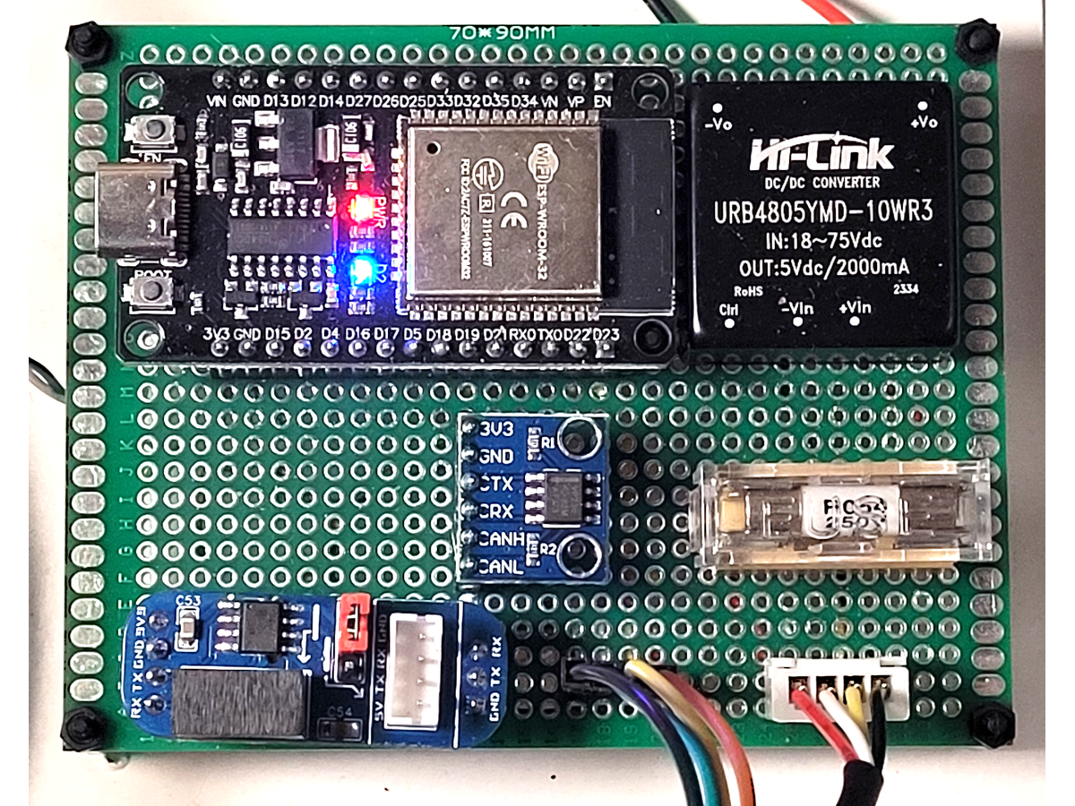 Photo of a green perfboard with an ESP32 development board, a black Hi-Link DC-DC converter module, a small blue CAN transceiver board and an RS485 adapter, all hand wired, with the ESP32 power LEDs lit
