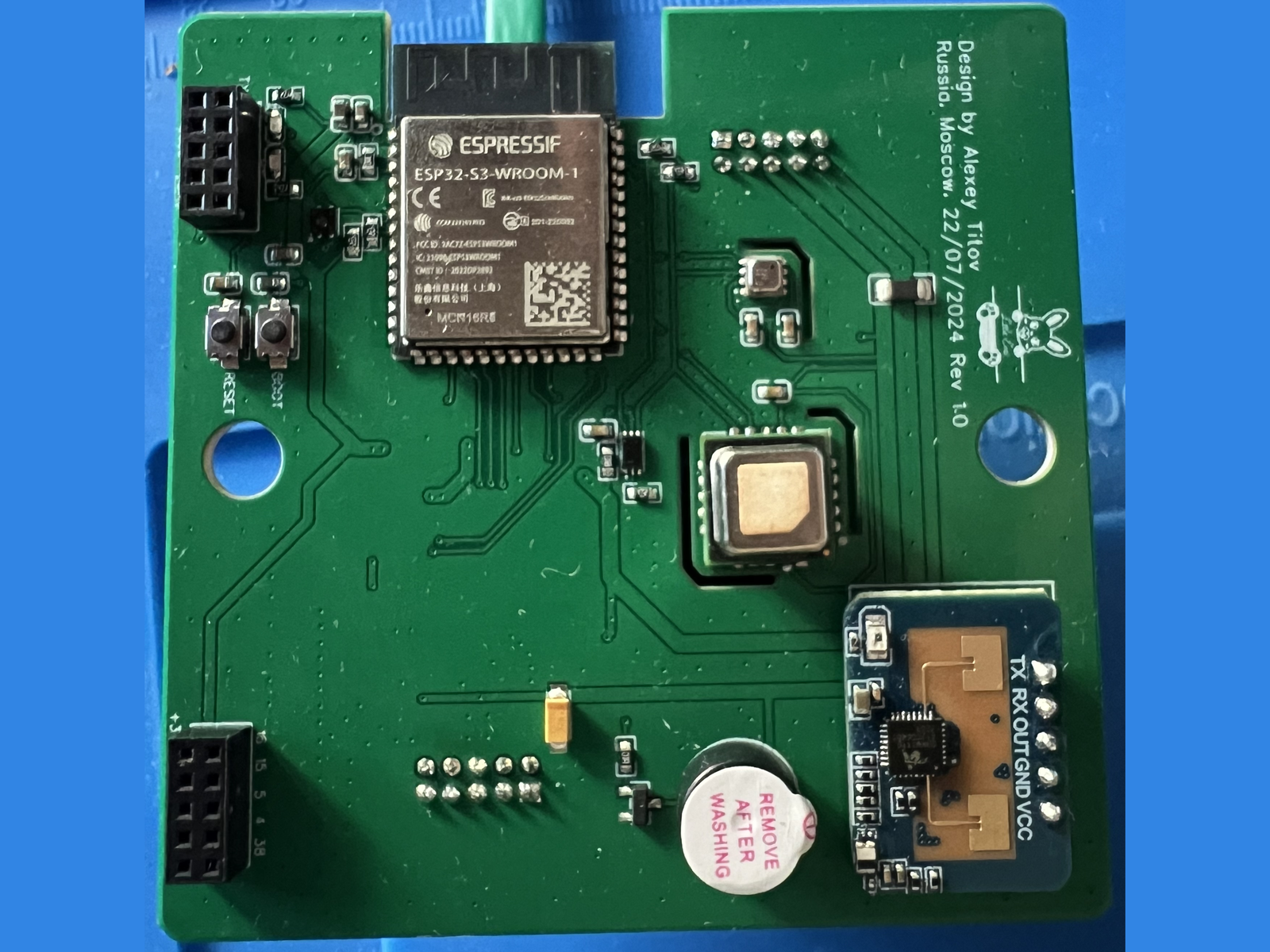Photograph of the assembled front board of the Eva sensor, a green square PCB carrying an ESP32-S3-WROOM-1 module, a metal-lidded SCD40 CO2 sensor, a buzzer, and a blue LD2410C radar module soldered along the right edge