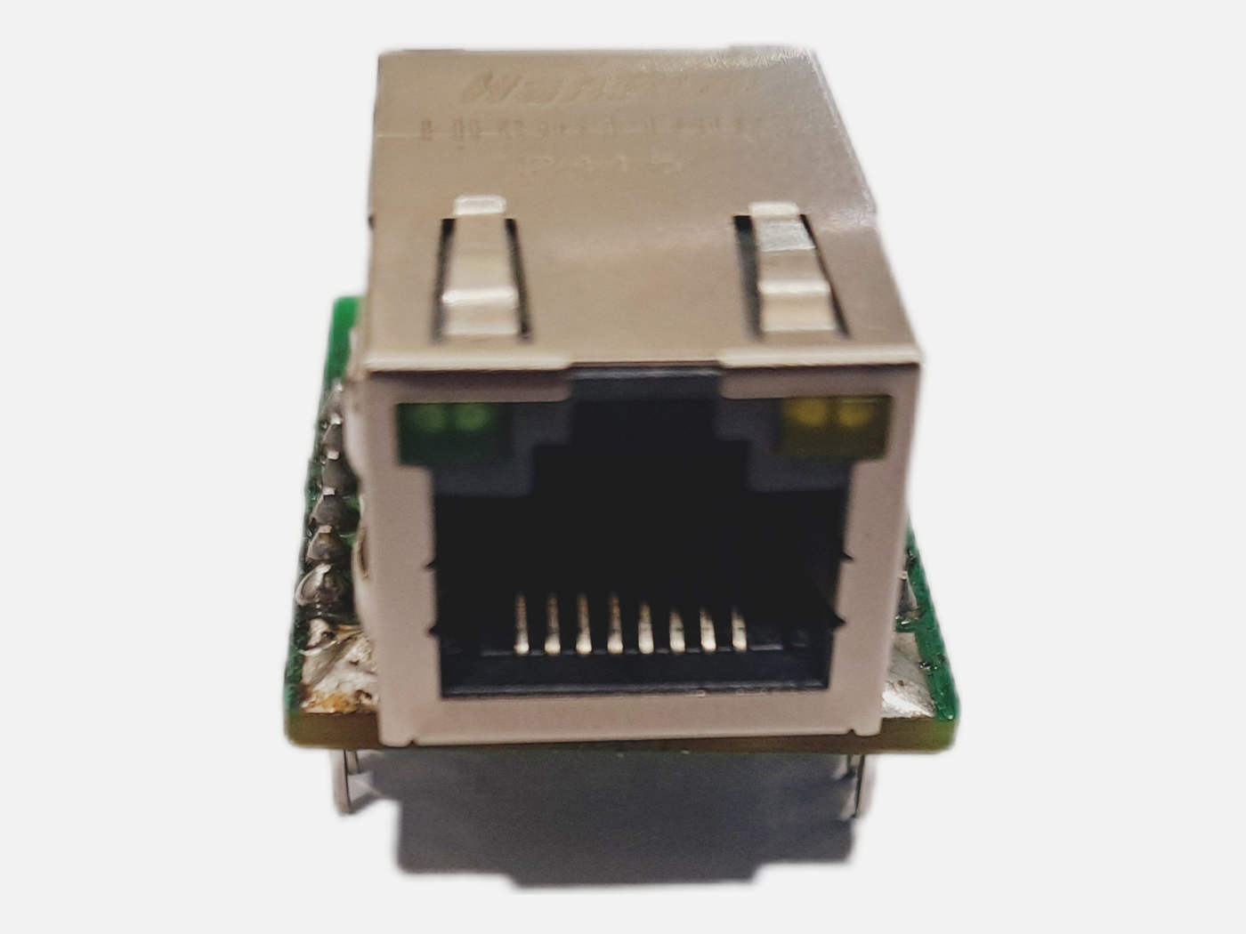 Front view photograph of the module showing the shielded RJ45 opening with eight gold contacts, a green status LED at the upper left and a yellow one at the upper right, the HanRun marking on the top of the shield, and hand soldered joints with flux residue on the green board edges