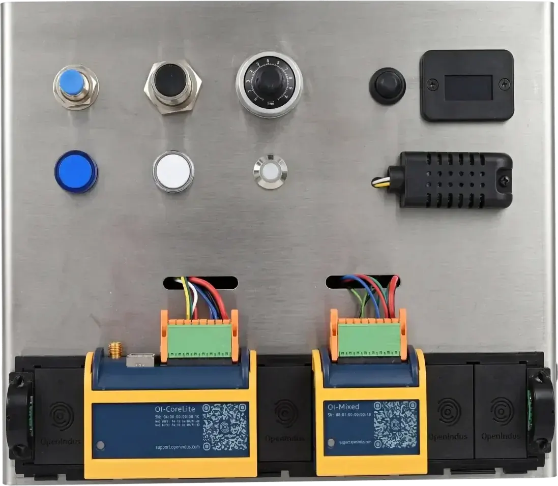 Stainless steel demo panel of the OpenIndus I/O kit with an OI-CoreLite and an OI-Mixed module clipped onto the black communication rail at the bottom, wired to pushbuttons, indicator lights, a potentiometer, a display and a temperature sensor above them