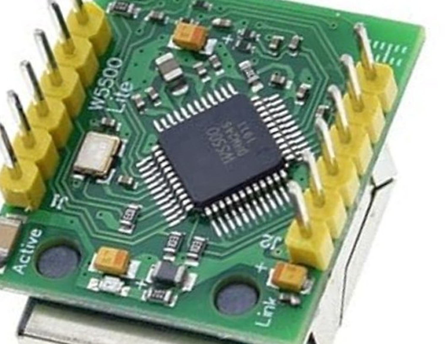 Close macro view of the underside of a small green Ethernet module, showing a black 48-lead quad flat pack marked W5500, a silver crystal can beside it, silkscreen text reading W5500 and Lite, two round indicator openings labelled Link and Active, and two rows of yellow six-pin headers